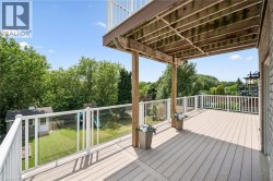Expansive outdoor deck featuring wood-finish flooring, white railings with glass panels, and a full ceiling overhead - 