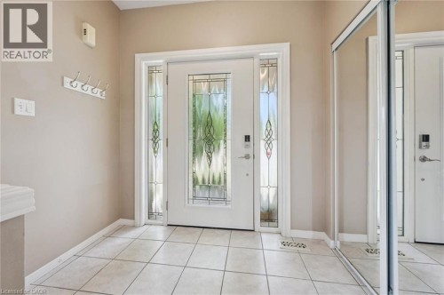 Entryway featuring a decorative glass front door, matching sidelights, and light-toned tile flooring - 426 Hidden Creek Drive, Kitchener, ON 