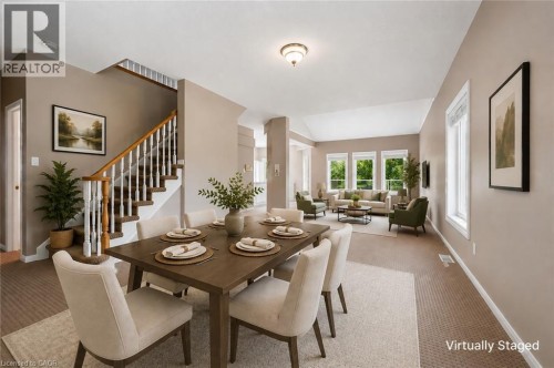 Open-concept dining and living areas, vaulted living room ceiling, multiple windows, and a classic staircase with wood-finish handrail - 426 Hidden Creek Drive, Kitchener, ON 