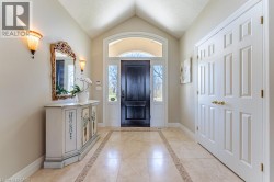 Vaulted ceiling entryway featuring a paneled front door with sidelights and an arched transom - 
