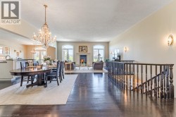 Elegant open-concept living space featuring hardwood flooring, a crystal chandelier, and abundant natural light from multiple windows - 
