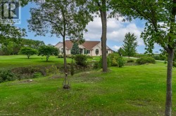 Expansive green lawn with mature trees and a gently sloped terrain - 