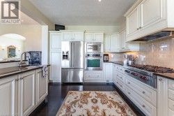 Kitchen featuring white cabinetry, dark countertops, stainless steel appliances, and a tiled backsplash - 