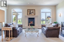 Living area featuring a stone mantel fireplace, arched windows, recessed lighting, and wood-finish flooring - 