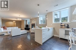 Open-concept living and kitchen featuring polished concrete flooring, a large center island with white cabinetry, pendant lighting, stainless steel appliances, and abundant natural light from multiple - 