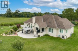 Stucco exterior featuring multiple windows and a brown shingled roof - 