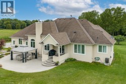 Expansive patio area featuring a built-in gazebo, stucco exterior, and multi-level paved steps - 