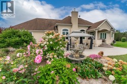 Stucco exterior with arched windows, a multi-tiered patio, a built-in gazebo, and extensive landscaping with a water feature - 