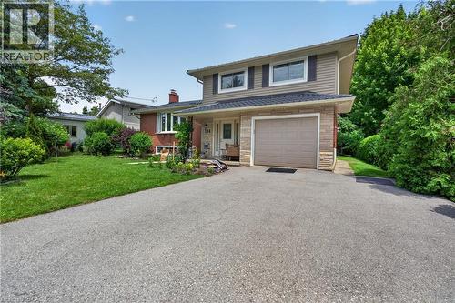 Two-story residence featuring a partial brick facade, attached single-car garage, and a paved driveway - 114 Shuh Avenue, Kitchener, ON 