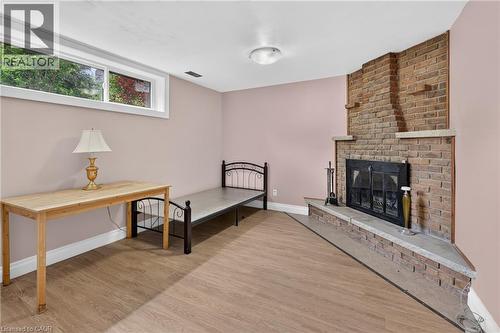 Brick fireplace with hearth, wood-finish flooring, and a single window - 114 Shuh Avenue, Kitchener, ON 