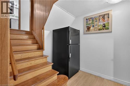 Wood staircase with spindle newel post, wood-finish flooring, and white walls - 114 Shuh Avenue, Kitchener, ON 