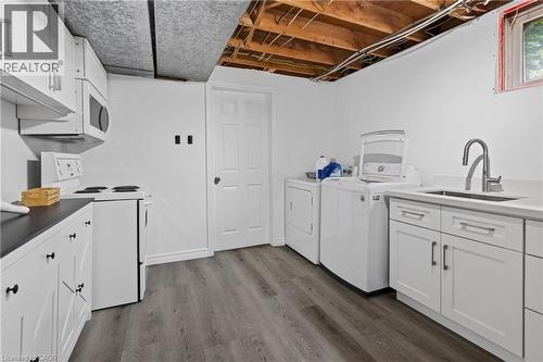 White cabinetry, integrated microwave, built-in range, wood-finish flooring, and a stainless steel sink with a high-arc faucet - 114 Shuh Avenue, Kitchener, ON 