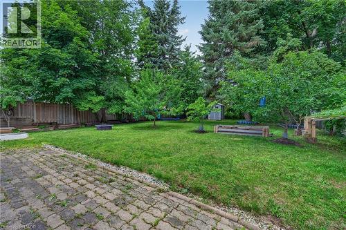 Expansive green lawn with mature trees and a paved patio area - 114 Shuh Avenue, Kitchener, ON 