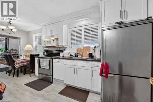 Kitchen featuring white cabinetry, stainless steel appliances, wood-finish flooring, and crown molding - 121 Panin Road, Burlington, ON 