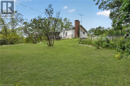 Expansive lawn featuring mature trees and a residential structure with a brick chimney - 121 Panin Road, Burlington, ON 