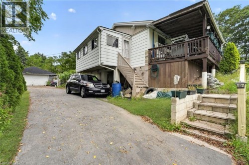 Paved driveway with an attached garage, a multi-level deck with wood railing, and exterior stairs leading to an upper level - 121 Panin Road, Burlington, ON 