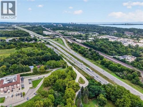 Expansive aerial perspective featuring a multi-lane highway, surrounding green spaces, and a body of water in the distance - 121 Panin Road, Burlington, ON 