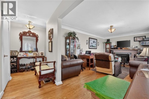 Hardwood flooring, painted interior walls, fireplace with brick surround, built-in wall sconces, and crown molding - 121 Panin Road, Burlington, ON 
