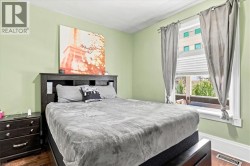 Single window with blinds and drapes, wood-finish flooring, and light green walls - 