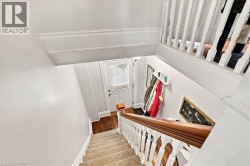 Staircase featuring wood-finish handrail, white balusters, and carpeted treads - 
