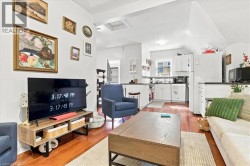 Open-concept living area featuring wood-finish flooring, white walls, and a recessed ceiling - 