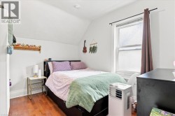 Hardwood-finish flooring, built-in shelving, white walls, window with curtain rod - 