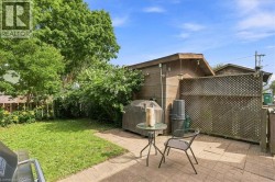 Paved patio area, manicured lawn, established perimeter landscaping, and a wooden lattice privacy screen - 