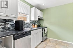 White cabinetry with brushed nickel hardware, dark countertops, a mosaic tile backsplash, stainless steel dishwasher, and a stainless steel range with overhead ventilation - 