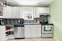 Kitchen featuring white cabinetry, mosaic tile backsplash, stainless steel dishwasher, stainless steel range, and tile flooring - 
