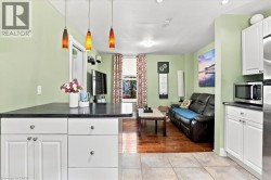 Kitchen featuring white cabinetry with dark countertops, three pendant lights, and tile flooring - 