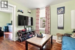 Hardwood flooring throughout, light green wall paint, interior doorway with trim, single window with blinds, and decorative wall shelving - 