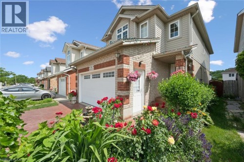 Brick and siding exterior with multiple dormers, an attached garage, and a paver driveway - 86 Bridlewreath Street, Kitchener, ON 