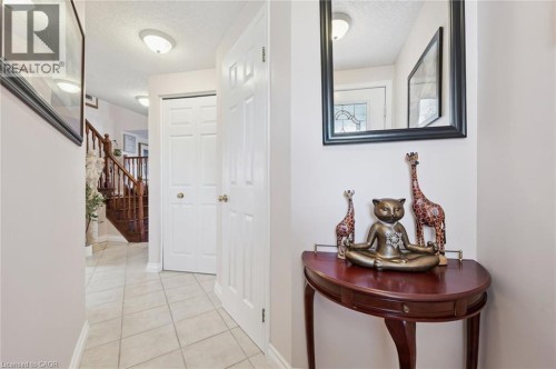 Tiled flooring throughout the entry, rich wood staircase with balusters, flat-panel interior doors, and flush-mount ceiling lighting - 86 Bridlewreath Street, Kitchener, ON 
