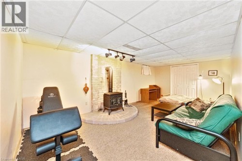 Wood-burning stove with a brick surround and hearth, track lighting, drop ceiling, and carpeted flooring - 41 Tuerr Drive, Kitchener, ON 