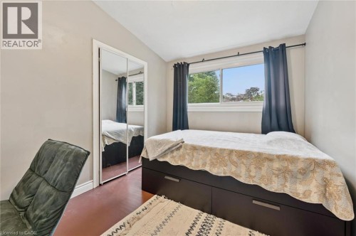 Mirrored sliding closet doors, a window with exterior scenery, and wood-finish flooring - 100 Forest Hill Drive, Kitchener, ON 