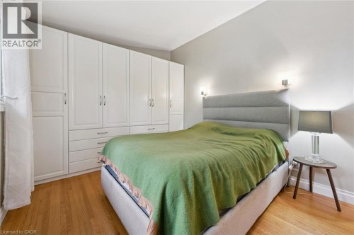 Hardwood flooring, extensive built-in white cabinetry, textured headboard, and dual wall sconces - 100 Forest Hill Drive, Kitchener, ON 