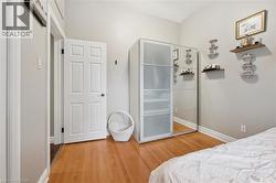 Wood-finish flooring with white baseboards, a paneled interior door, and light gray wall finishes - 