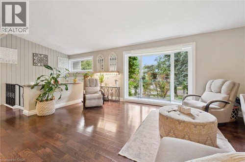Rich wood-finish flooring throughout, featuring a bay window, a half wall with railing, and a window with a shelf - 100 Forest Hill Drive, Kitchener, ON 