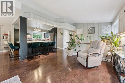 Hardwood flooring, kitchen island with seating, stainless steel appliances, pendant lighting, and shiplap accent wall - 100 Forest Hill Drive, Kitchener, ON 