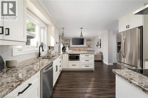 Kitchen featuring white cabinetry with matte black hardware, stainless steel appliances, speckled stone countertops, and wood-finish flooring - 20 San Marino Crescent, Hamilton, ON 
