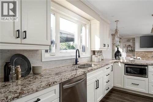 Kitchen featuring white shaker cabinetry, stainless steel dishwasher, undermount sink with matte black faucet, speckled stone countertops, and built-in microwave - 20 San Marino Crescent, Hamilton, ON 