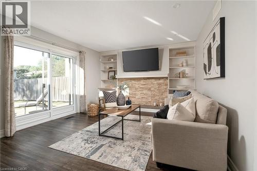 Spacious living area featuring dark wood-finish flooring, a stone-clad fireplace, and built-in shelving - 20 San Marino Crescent, Hamilton, ON 