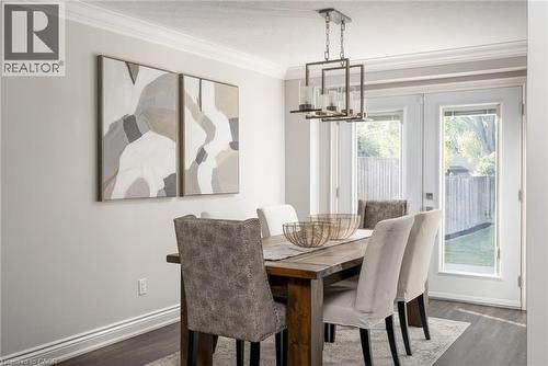 Formal dining area featuring wood-finish flooring, a contemporary chandelier, crown molding, and double glass-paneled doors leading to the exterior - 20 San Marino Crescent, Hamilton, ON 