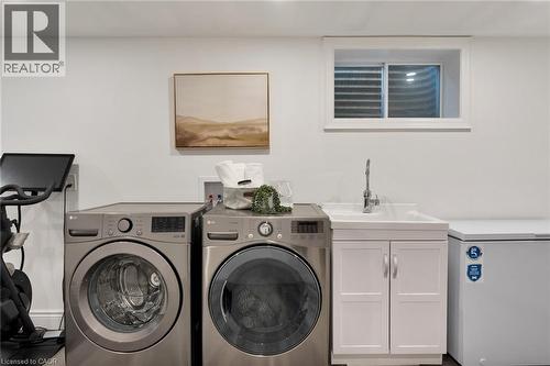Laundry area featuring a large window, a utility sink with white cabinetry, and light-toned walls - 20 San Marino Crescent, Hamilton, ON 