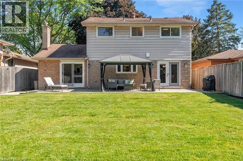 Expansive green lawn with a brick and siding exterior, featuring multiple windows, a sliding glass door, and a single exterior door - 20 San Marino Crescent, Hamilton, ON 