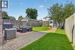 Expansive backyard featuring a brick paver patio, lush green lawn, and a charming storage shed - 