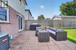 Brick and siding exterior with a sliding glass door, leading to a patio with paver stones and a fenced perimeter - 