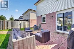 Expansive brick paver patio with a sliding glass door entry, exterior wall sconce, and white window trim - 