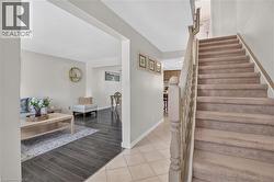 Carpeted staircase with wooden banister, laminate flooring, and light-toned wall paint - 