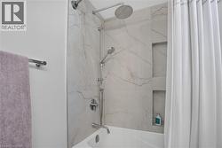 Bathtub with a shower system featuring a rain showerhead, hand-held shower, and chrome fixtures - 
